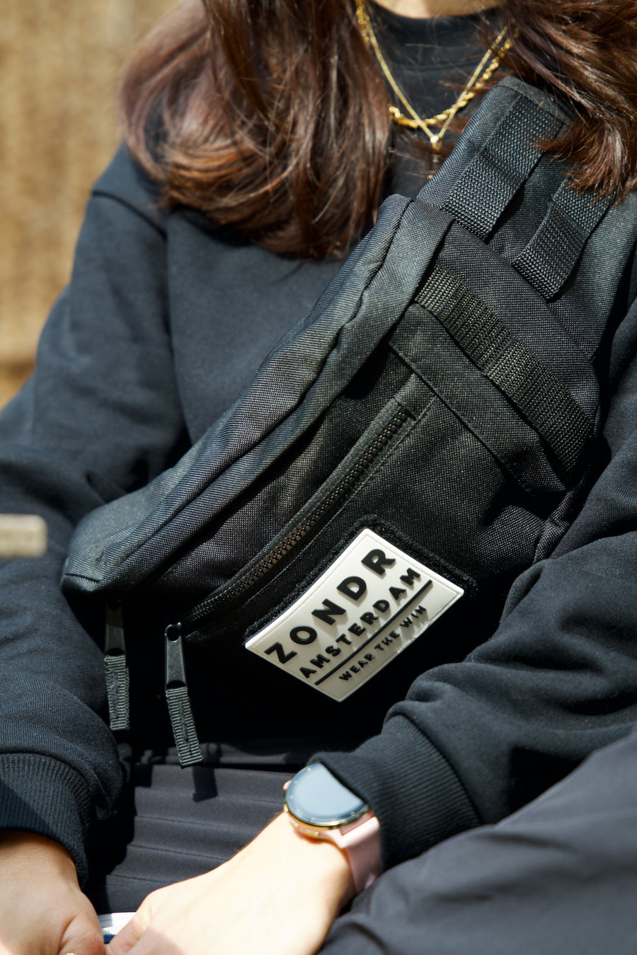 Close-up of a black ZONDR DAILY CARRY crossbody bag with the ZONDR Amsterdam patch, worn across the body